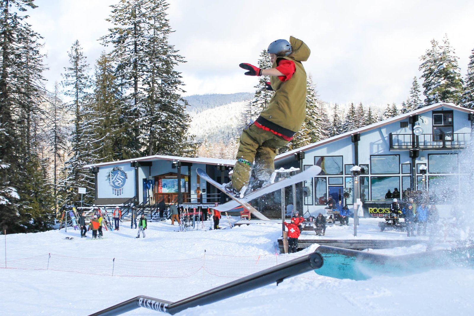 Snowboarder at 49 Degrees North going off a rail at a shred event.