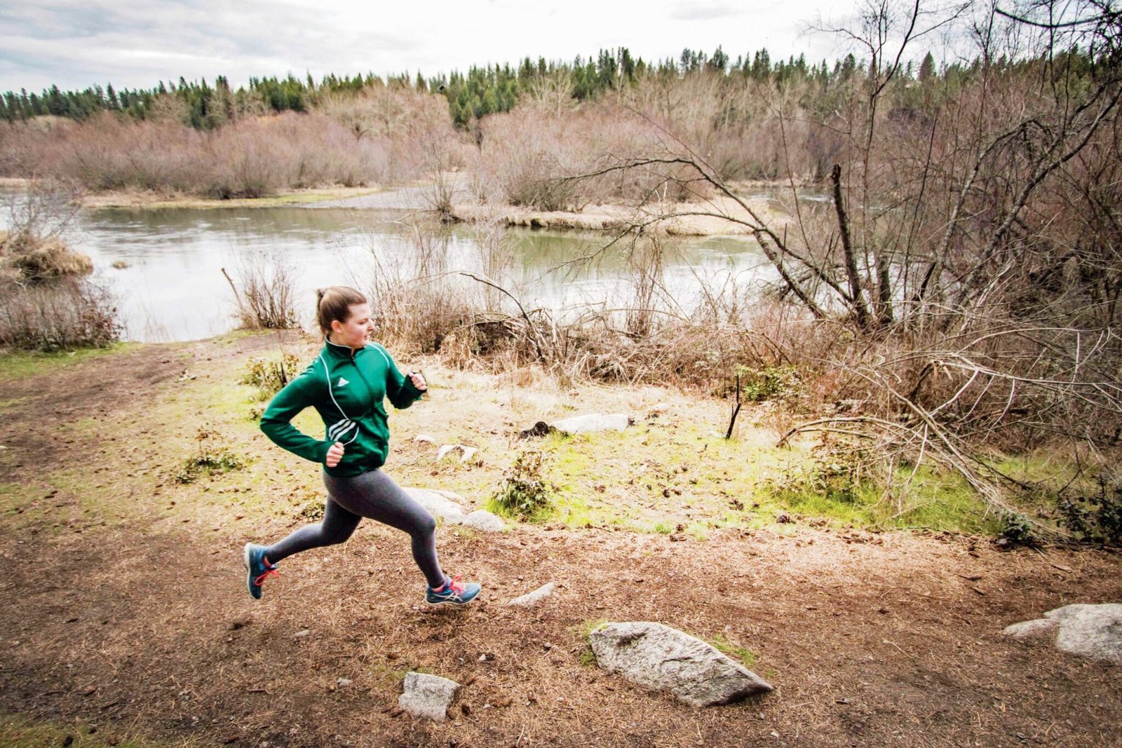 A woman running along a river trail.