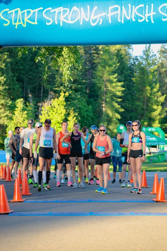 vertical picture of racers at starting line for Coeur d'Alene marathon, standing under an large inflated banner that says "Start Strong, Finish Stronger."