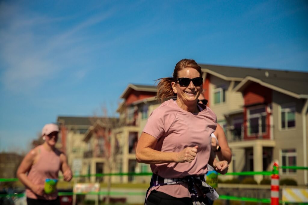 Female runner smiling for the camera while racing in The Split Half Marathon & 5k event that goes through the Kendall Yards neighborhood in downtown Spokane. Photo courtesy Negative Split.