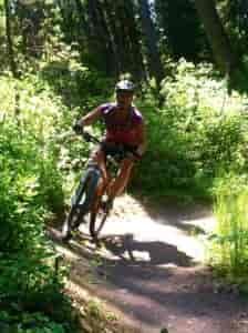 Woman mountain biking on a dirt trail.