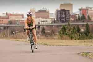 Woman cycling on the Spokane Centennial Trail with view of downtown Spokane in the background.