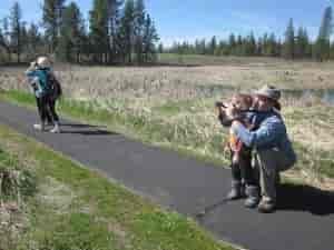 Parent and child on a trail at Turnbull National Wildlife Refuge -- looking through binoculars for birdwatching.