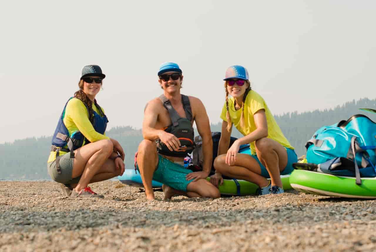 Grace, Jed, and Allie crouch near their paddle boards on land (Photo: Jed Conklin Photography)