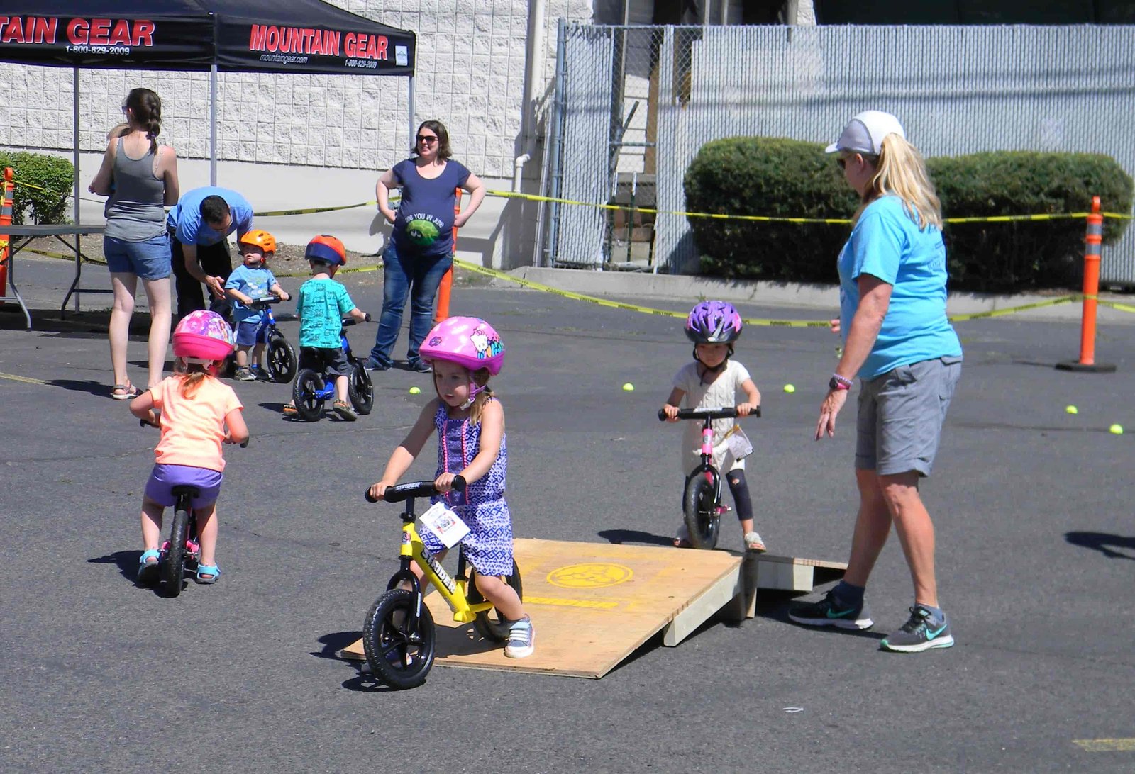 Kids ride strider bikes over a small ramp to hone their balance skills.