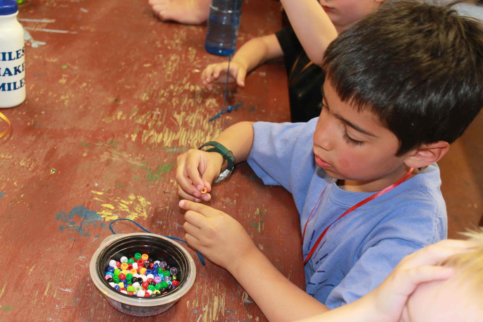 A boy strings beads for the start of a solid friendship bracelet (Photo: Camp Fire Inland Northwest)