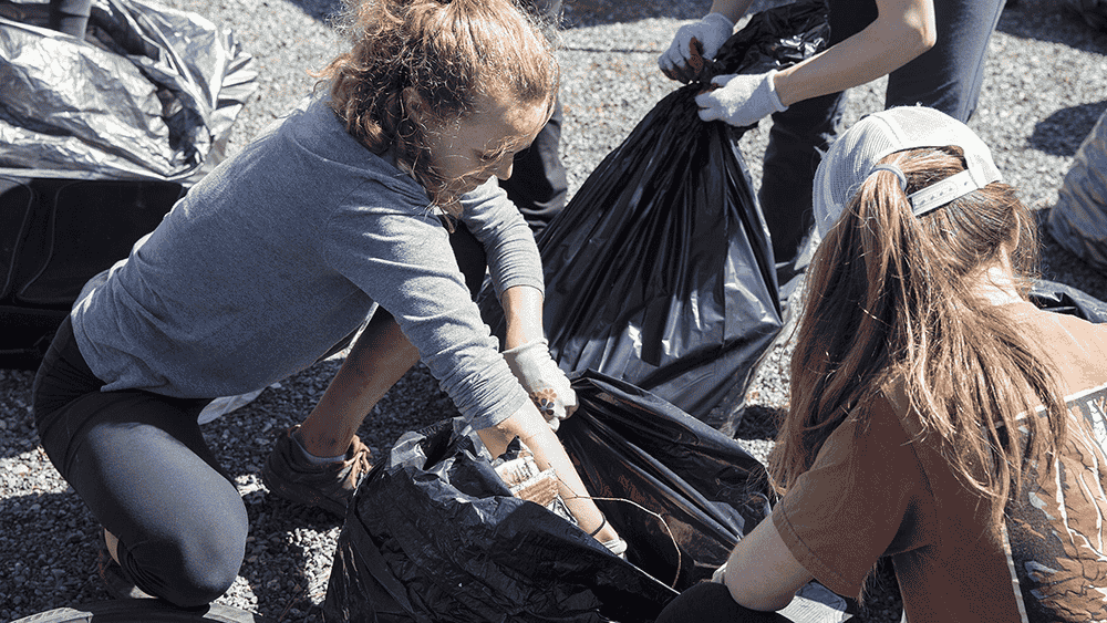 Photo of climbers placing trash in garbage bags.