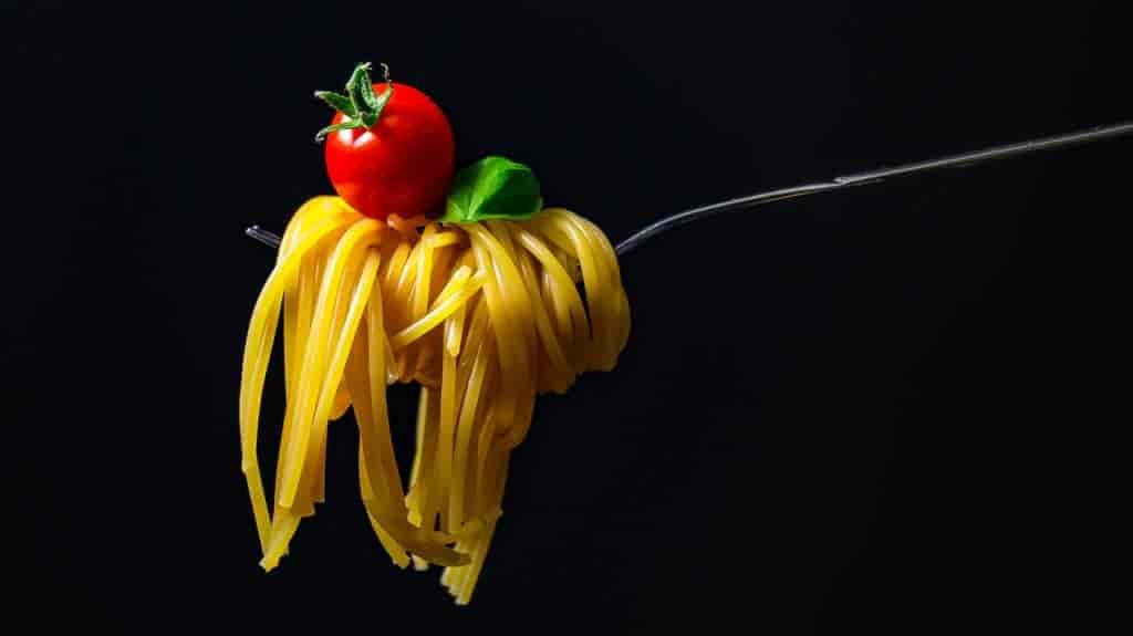 Photo of spaghetti on fork with tomato on top.