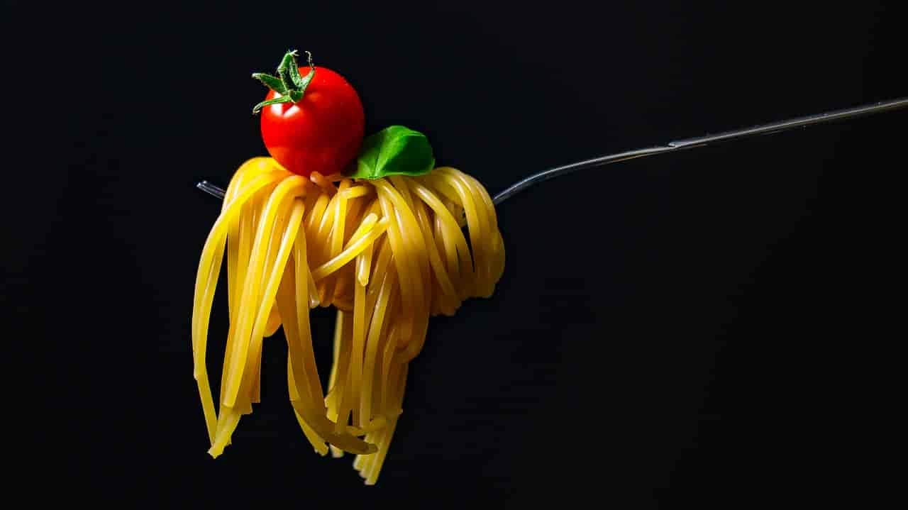 Photo of spaghetti on fork with tomato on top.