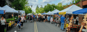 Photo of farmers market with people shopping at various stalls.