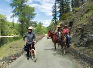 Photo of biker and two horses with riders stopped on the Ferry County Rail Trail.
