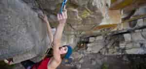 Photo of climber clipping on a lead route in Pack Rat Cave.
