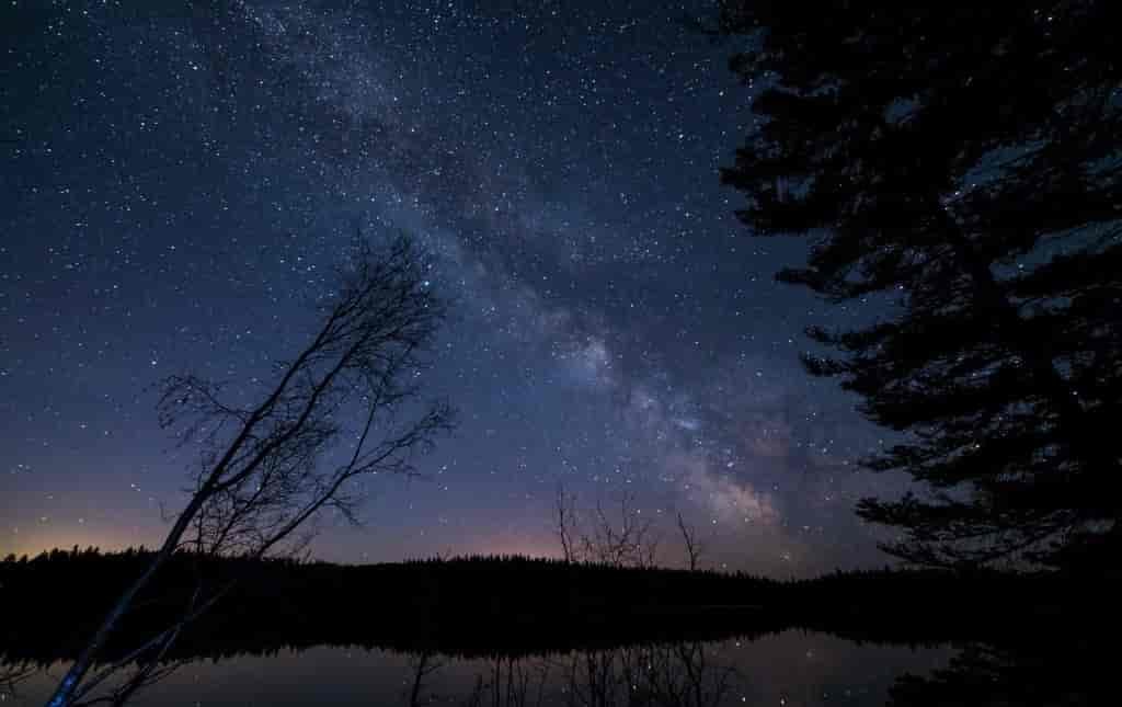 Photo of a lake with stars above.