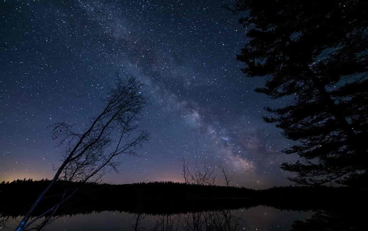 Photo of a lake with stars above.