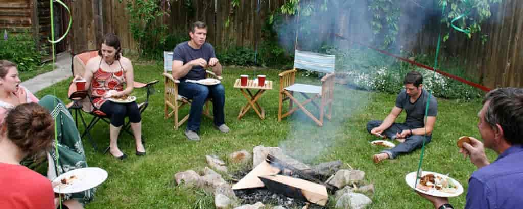 Photo of people gathered around a campfire in a backyard.