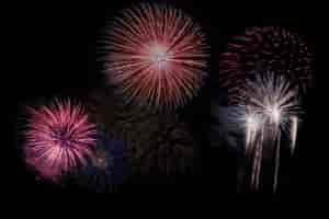 Red, white, and pink fireworks at night.