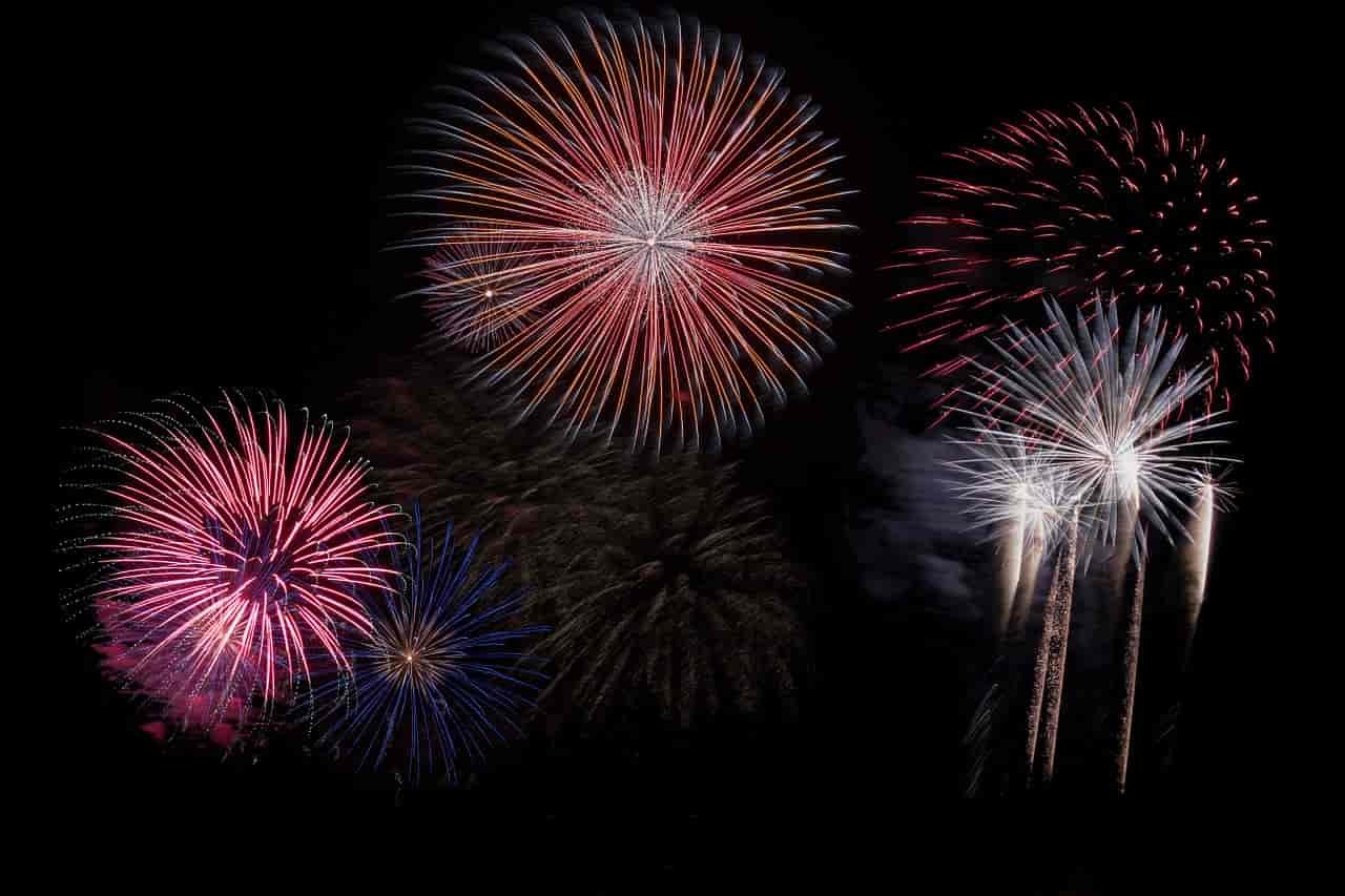 Red, white, and pink fireworks at night.