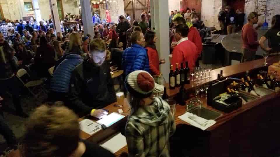 Man gets beer at a bar in room packed w people