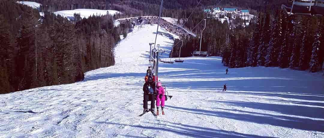 Photo taken from afar of father and daughter riding the chairlift at Mount Spokane.