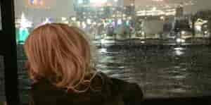Photo of kid taken from behind looking out window at fireworks.