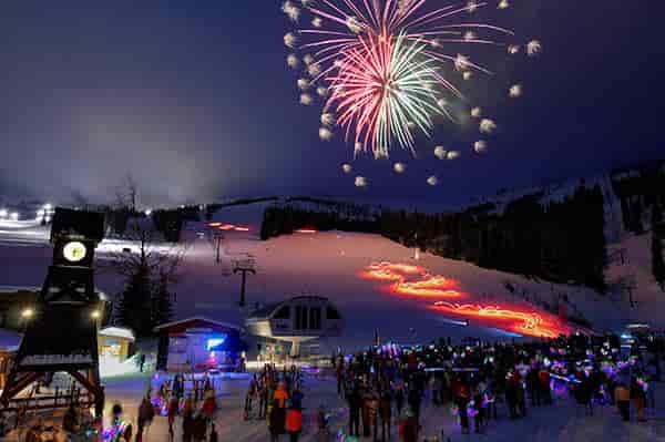 Photo of crowd looking at fireworks over ski hill.