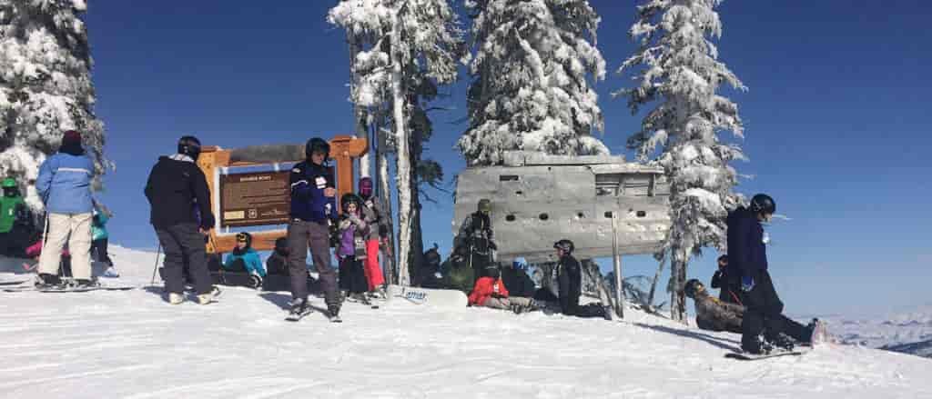 Photo of skiers and boarders standing in front of the bomber's wing and a plaque on Mission Ridge.