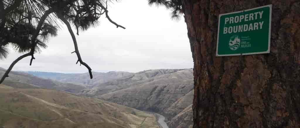 Close up view of the property boundary sign on a tree and the Grande Ronde River in the background.