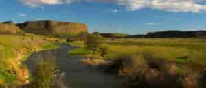 Photo of creek with butte in background.
