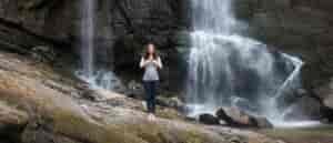 Photo of person practicing yoga in front of waterfall.