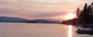 Sunset at Lake Pend Oreille, with rich hues of pink, yellow, and orange in the sky.