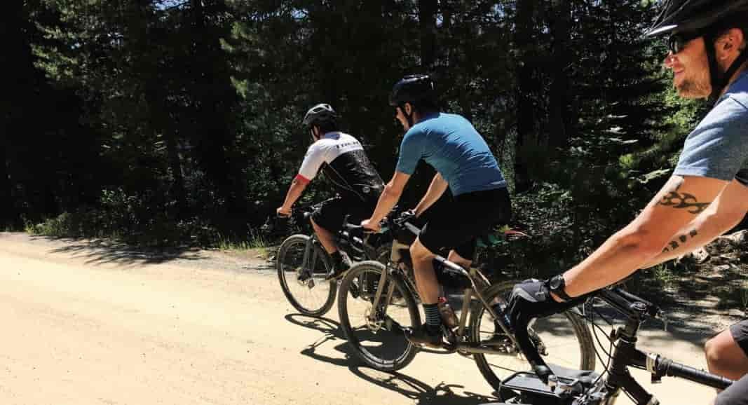 People riding gravel bikes on a dirt road.