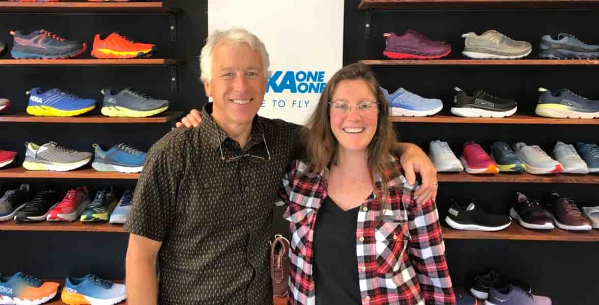 Two people posed in front of a shoe wall.