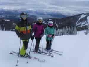 A group of kid skiers on top of a mountain.