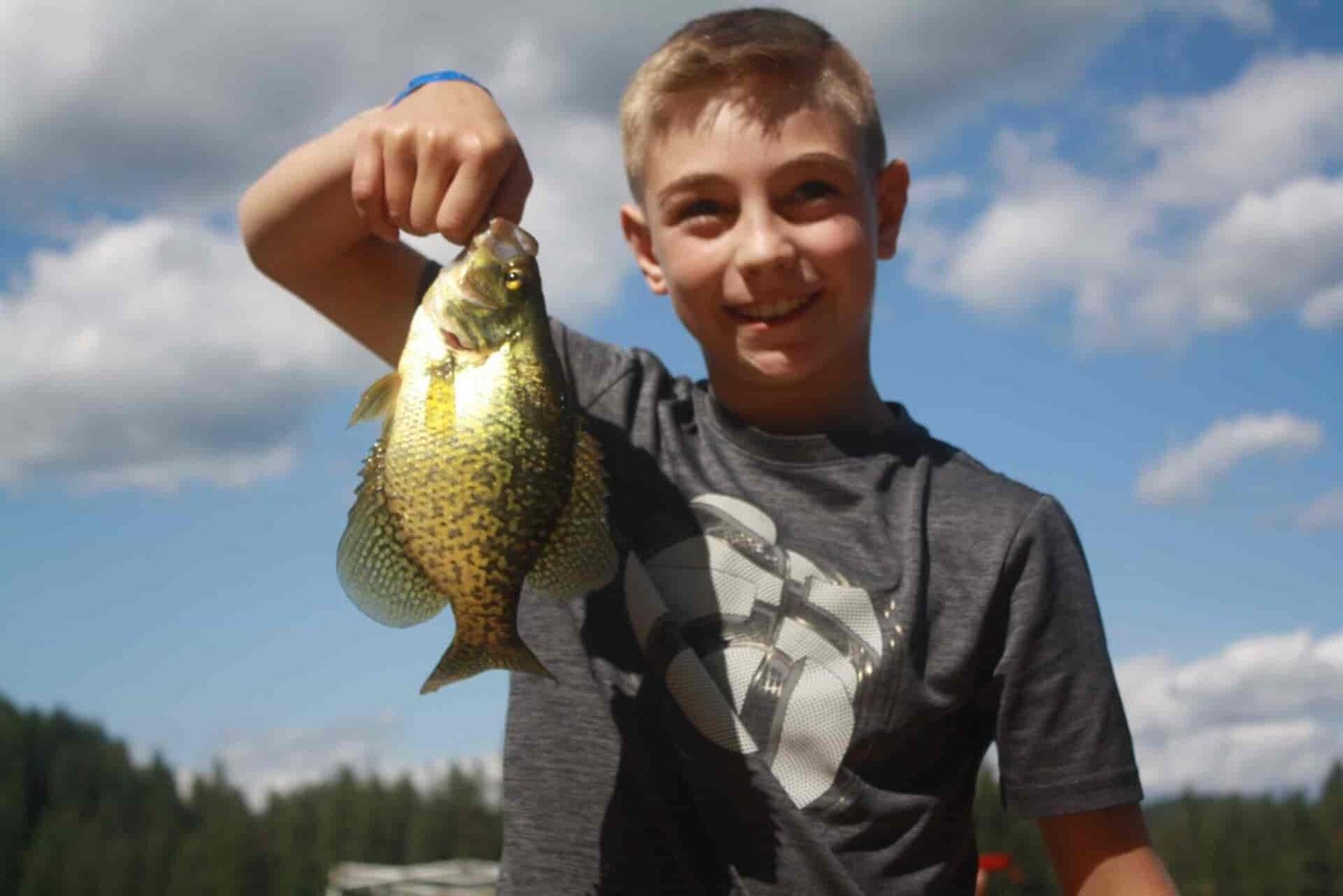 A teen boy holding a fish.