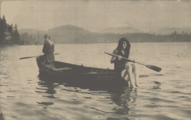 A old black and white vintage photo of two women canoeing.