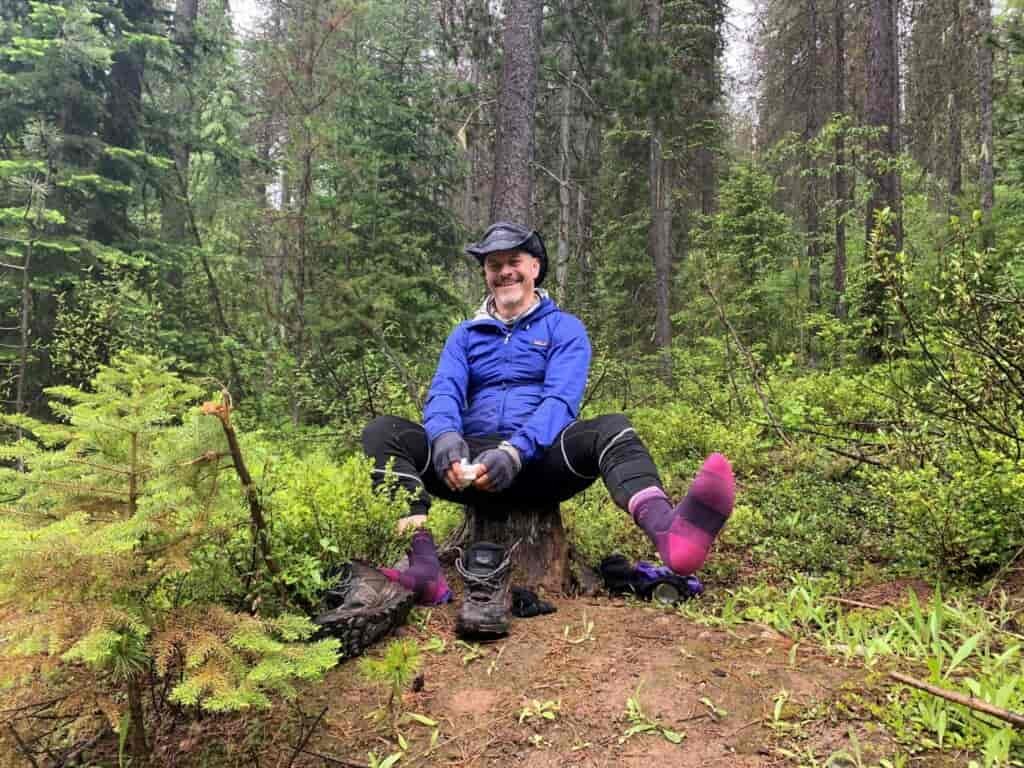Man with a cowboy hat on and pink socks with no shoes.
