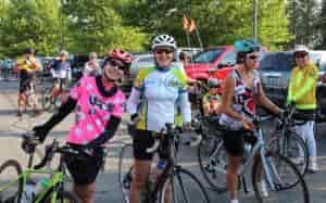 Two women on bikes, wearing clothing gear and helmets, smiling at the camera, surrounded by other cyclists during Spokane Valley's Cycle Celebration.