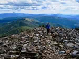 Hiker standing atop shale rocks on the summit of Abercrombie Mountain.