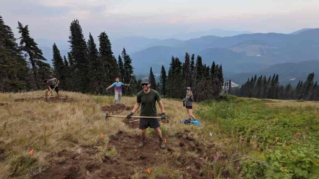 Trail building volunteers holding pulaski tools as they work at Mount Spokane.