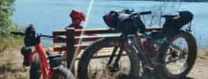 Child and parent taking a rest-break while biking on a trail above Fish Lake, with bikes resting against a bench.