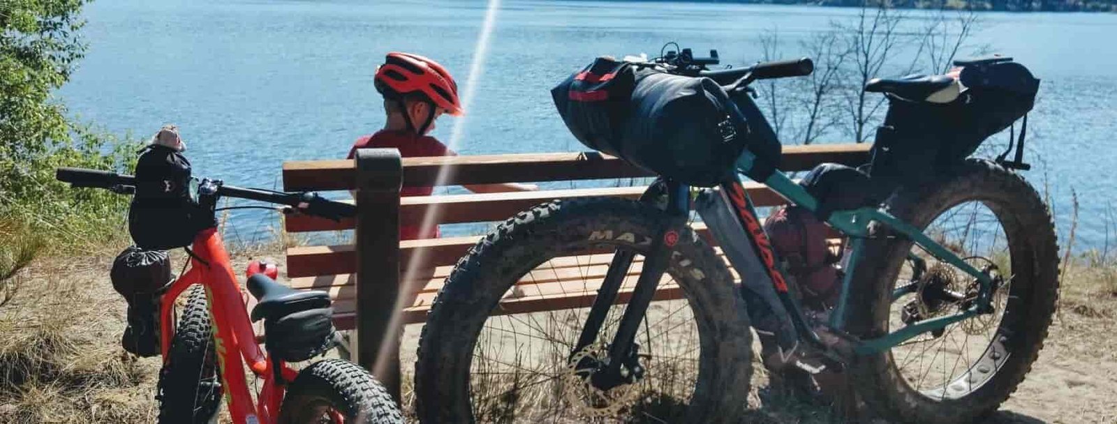 Child and parent taking a rest-break while biking on a trail above Fish Lake, with bikes resting against a bench.