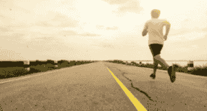 person running along an empty roadway with sunset colors on a flat horizon.