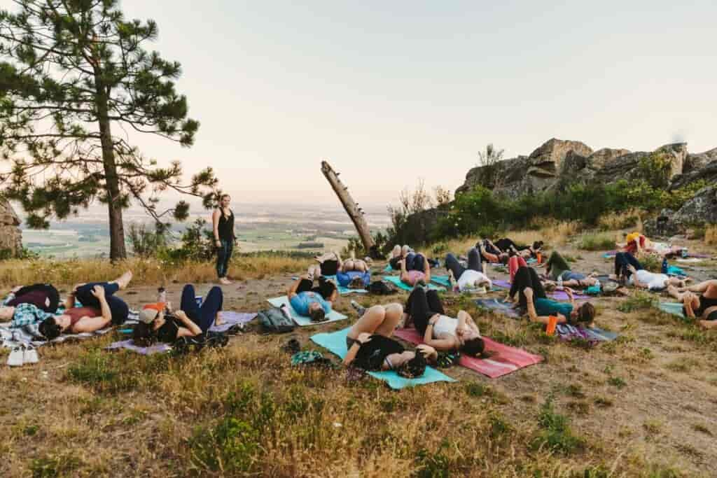 Women on yoga mats in a meadow setting, with yoga mats on dirt.