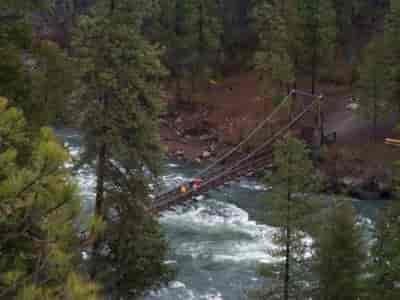 Swinging bridge over the Spokane River and its raging whitewater rapids at the Bowl and Pitcher area of Riverside State Park.